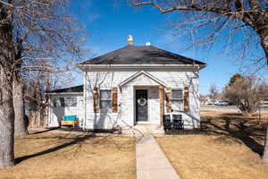 View of front of home with a chimney, a front lawn, and a shingled roof