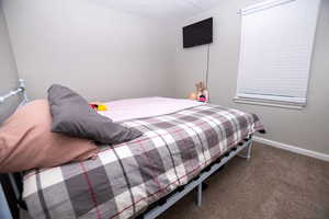 Carpeted bedroom featuring baseboards and a textured ceiling