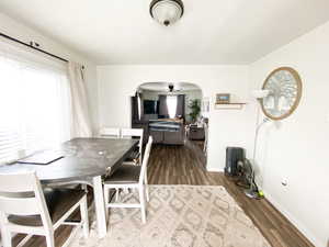 Dining space featuring arched walkways, ceiling fan, healthy amount of natural light, and dark wood-style floors