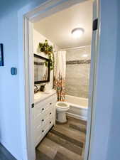 Full bath with shower / bath combination with curtain, vanity, and dark wood-style floors
