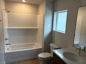 Bathroom with vanity, washtub / shower combination, and dark wood finished floors