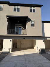 Back of property featuring stucco siding, driveway, a balcony, and an attached garage