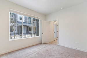 Spare room with baseboards and light colored carpet