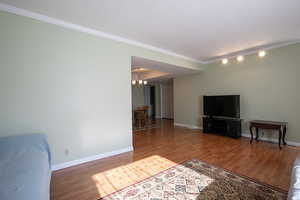 Unfurnished living room with ornamental molding, a chandelier, LVP floors