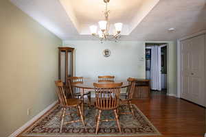Dining space with hanging lights, wood finished floors, a textured ceiling, and a tray ceiling