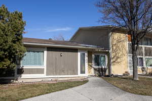 Property entrance featuring a lawn and roof with shingles