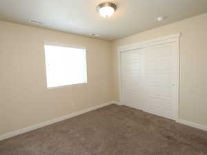 Unfurnished bedroom featuring carpet and a closet