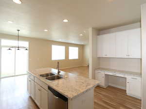 Kitchen with light wood-style floors, built in desk, and white cabinets