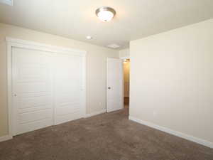 Unfurnished bedroom featuring a closet and dark colored carpet
