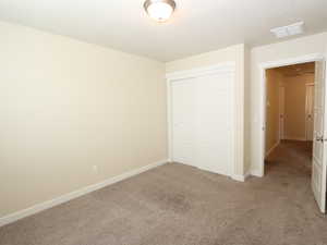 Unfurnished bedroom featuring light carpet and a closet