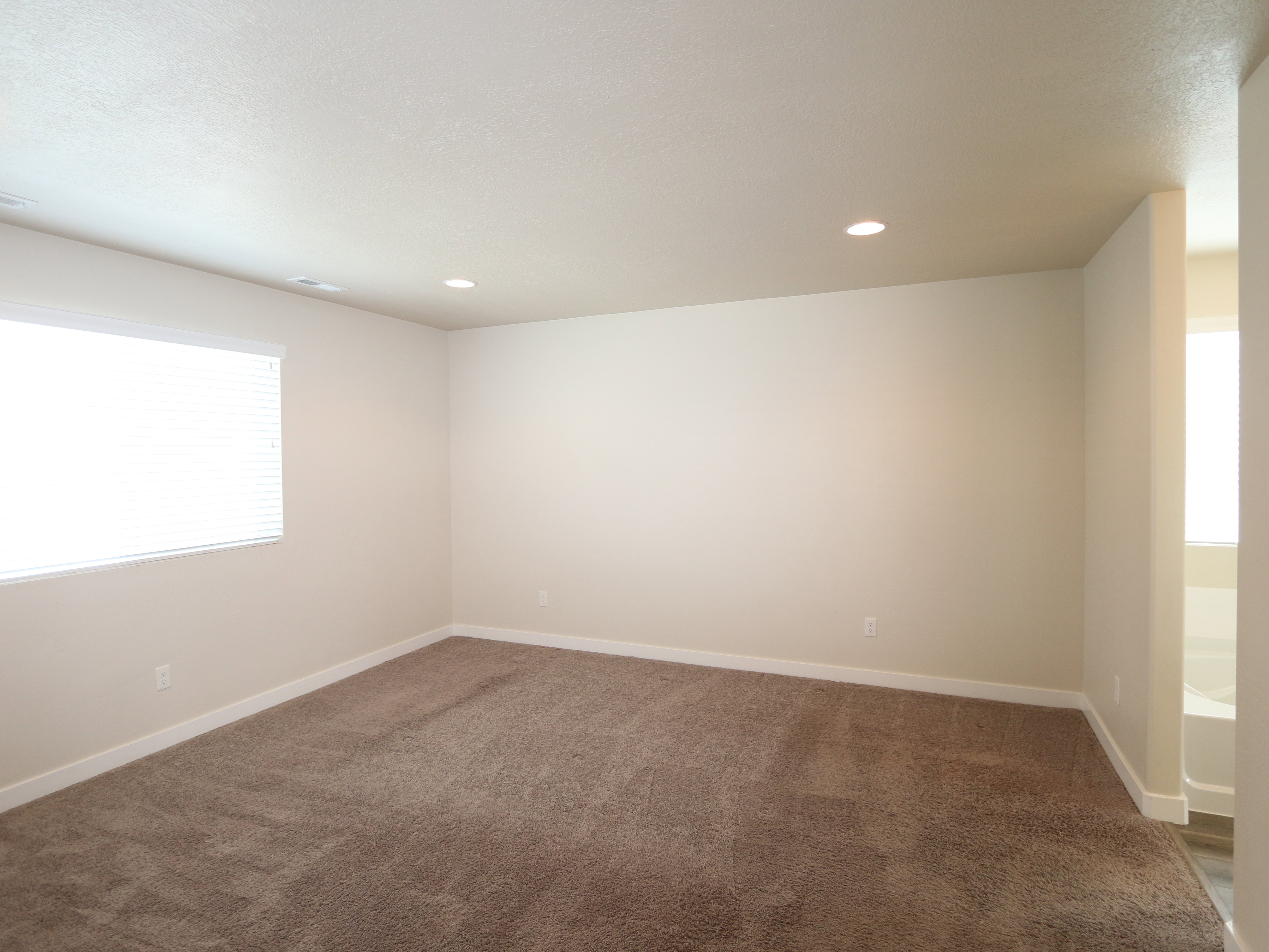 Empty room with healthy amount of natural light, dark colored carpet, and recessed lighting