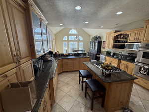 Kitchen featuring a breakfast bar, hanging lights, light tile patterned floors, and stainless steel appliances