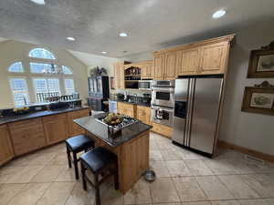 Kitchen with a kitchen breakfast bar, open shelves, stainless steel appliances, a kitchen island, and suspended lighting