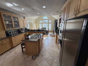 Kitchen featuring glass fronted cabinets, stainless steel appliances, a kitchen bar, dark stone counters, and a center island