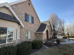 View of property exterior featuring stone siding, brick siding, a lawn, and stucco siding