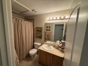 Full bath with vanity, a shower with curtain, a textured ceiling, a textured wall, and light tile patterned floors