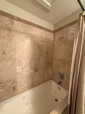 Full bath featuring a combined bath / shower with jetted tub and a textured ceiling