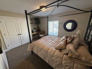 Carpeted bedroom featuring a closet and a textured ceiling