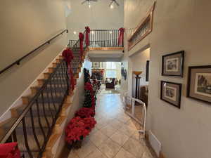 Stairway with tile patterned flooring, a high ceiling, and a ceiling fan