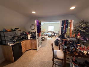 Kitchen featuring lofted ceiling, dark countertops, black refrigerator, light colored carpet, and recessed lighting