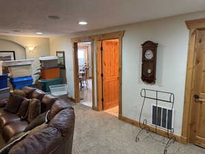 Living room featuring light carpet, recessed lighting, and a textured wall