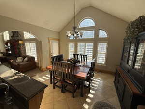 Dining space featuring a high ceiling, hanging lights, arched walkways, and light tile patterned floors