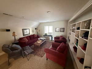 Carpeted living area with lofted ceiling and baseboards