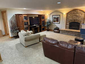 Carpeted living room with a stone fireplace and recessed lighting