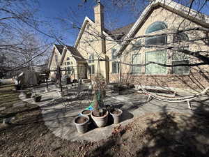 Rear view of property featuring a patio, a chimney, and outdoor dining space