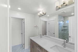 Bathroom with a marble finish shower, double vanity, and light marble finish flooring