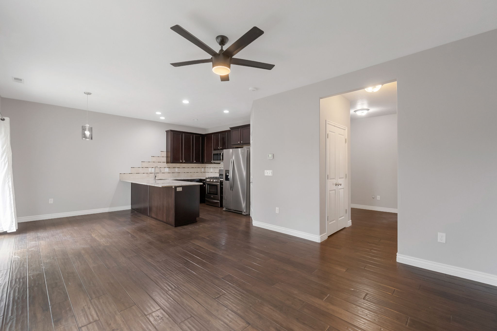 Kitchen with dark wood finish cabinets, a peninsula, stainless steel appliances, ceiling fan, and decorative light fixtures