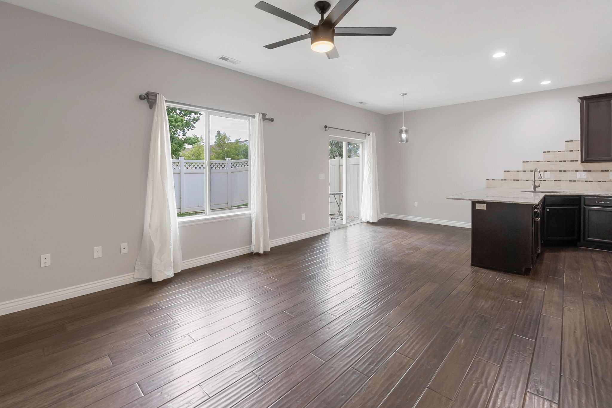 Unfurnished living room with a ceiling fan, recessed lighting, and dark wood-style floors