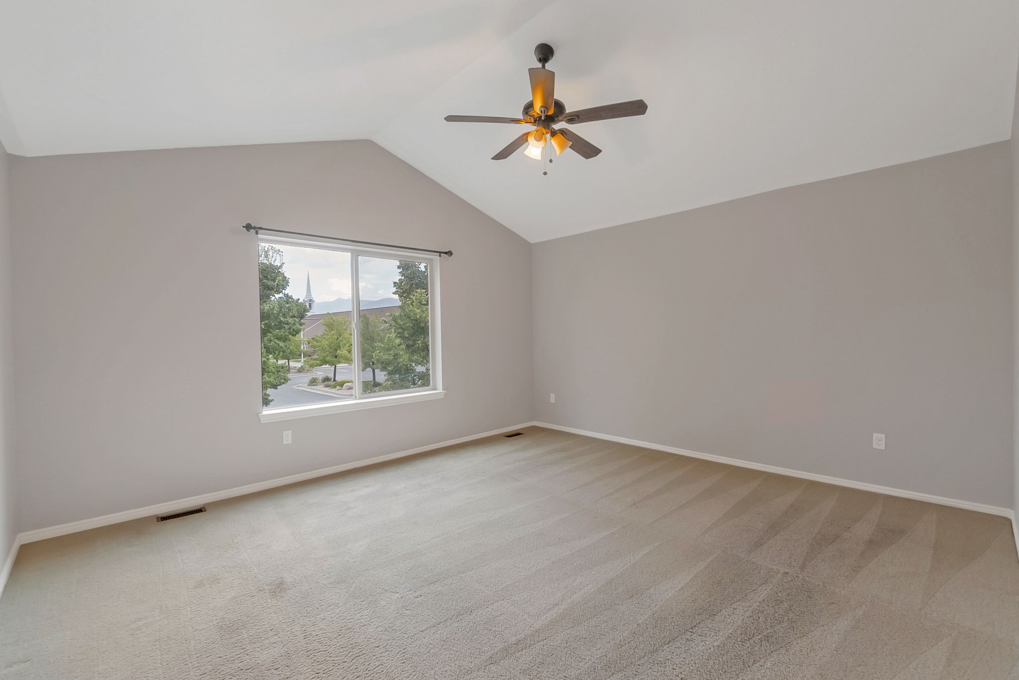 Spare room featuring light colored carpet and a ceiling fan