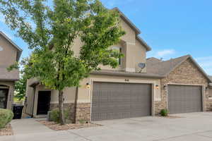 Traditional-style home featuring stone siding, concrete driveway, and stucco siding