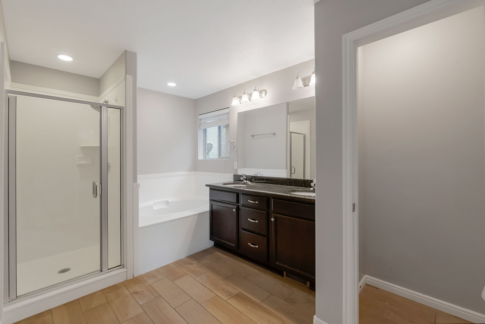 Full bathroom featuring a stall shower, double vanity, a garden tub, and wood tiled floors