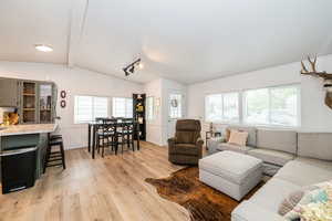 Living room featuring vaulted ceiling with beams and light wood-style flooring