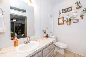 Bathroom featuring vanity, a ceiling fan, light tile patterned floors, and a walk in closet