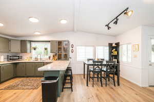 Kitchen featuring a breakfast bar, light countertops, light wood-type flooring, a peninsula, and green cabinetry
