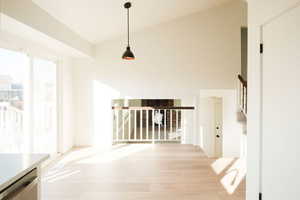 Unfurnished dining area featuring vaulted ceiling and light wood-style floors