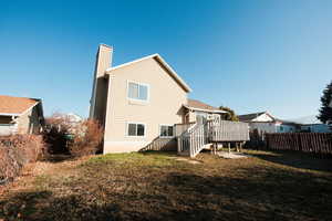 Back of house with a wooden deck and a chimney