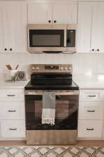 Kitchen featuring stainless steel appliances, white cabinetry, light stone counters, and tasteful backsplash