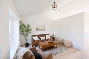 Living area with vaulted ceiling and wood finished floors