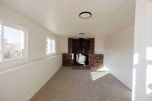 Unfurnished living room featuring a wood stove and carpet flooring