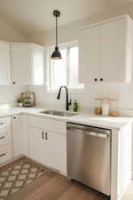 Kitchen featuring white cabinetry, dishwasher, and hanging light fixtures