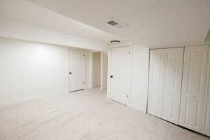 Unfurnished bedroom featuring light carpet, a textured ceiling, and a closet