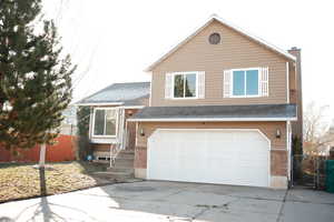 View of front of property with a garage, driveway, and a shingled roof
