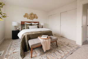 Bedroom with two closets and light colored carpet