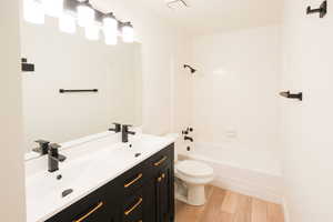 Full bathroom featuring double vanity,  shower combination, and light wood-type flooring