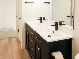 Bathroom with double vanity and light wood-type flooring