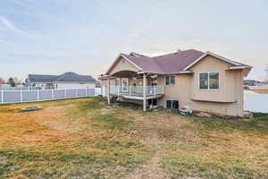 Back of house featuring a fenced backyard, a deck, and a shingled roof